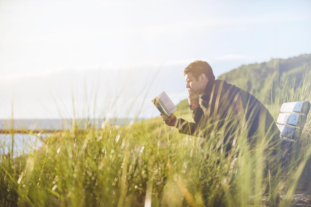 Ein Mann sitzt auf einer Bank und liest ein Buch