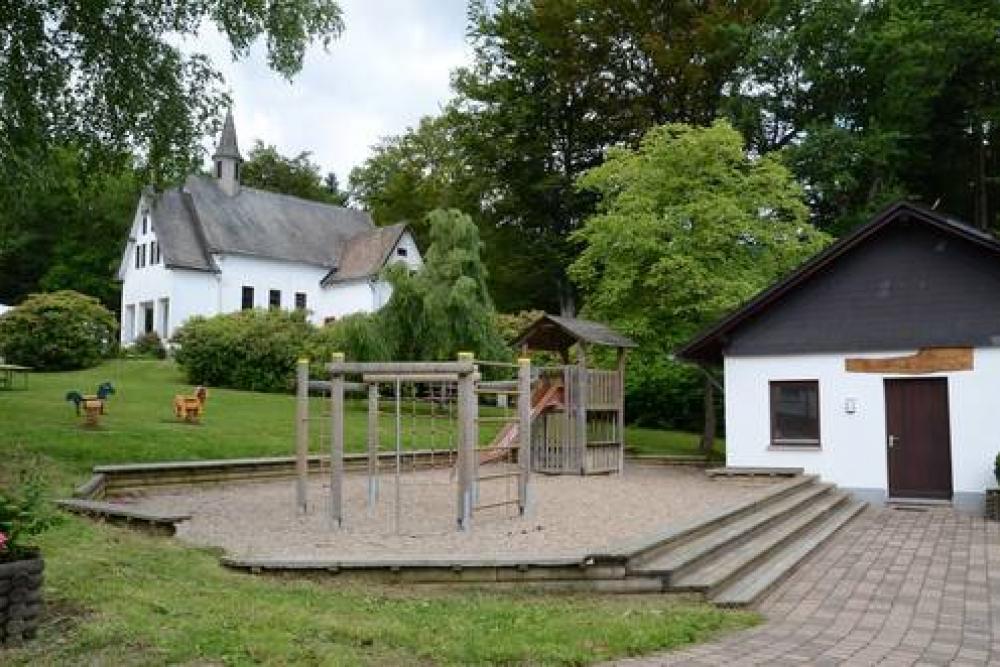 Spielplatz und Spielhaus mit Kapelle im Hintergrund