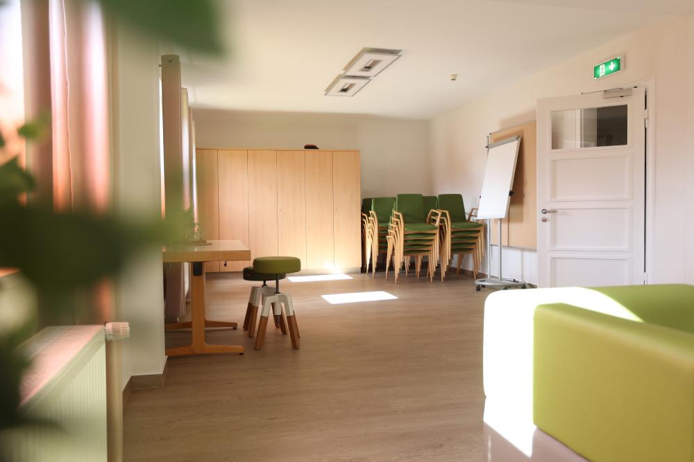 Heller Gruppen- und Seminarraum mit flexibler Bestuhlung, Flipchart und gemütlichem Sitzbereich für Besprechungen und Workshops.