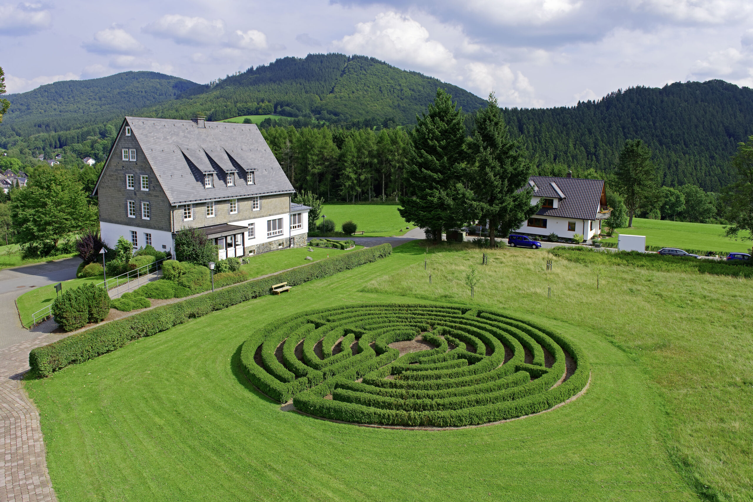 Eingebettet in die sanfte Mittelgebirgslandschaft liegt ein Bildungshaus mit Labyrinthgarten – ein Ort für Begegnung, Reflexion, Spiritualität und persönliche Entwicklung in naturnaher Umgebung.