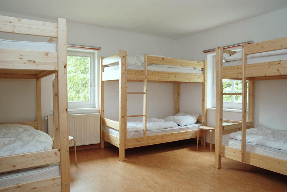 Mehrbettzimmer mit Etagenbetten aus Holz und heller, funktionaler Ausstattung für Gruppen und Gemeinschaftsaufenthalte.